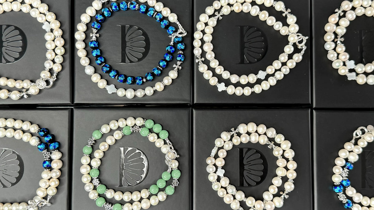 Colliers de perles de culture d’eau douce enroulés sur des écrins noirs DAÏQUIRI, certains avec des perles bleues ou vertes