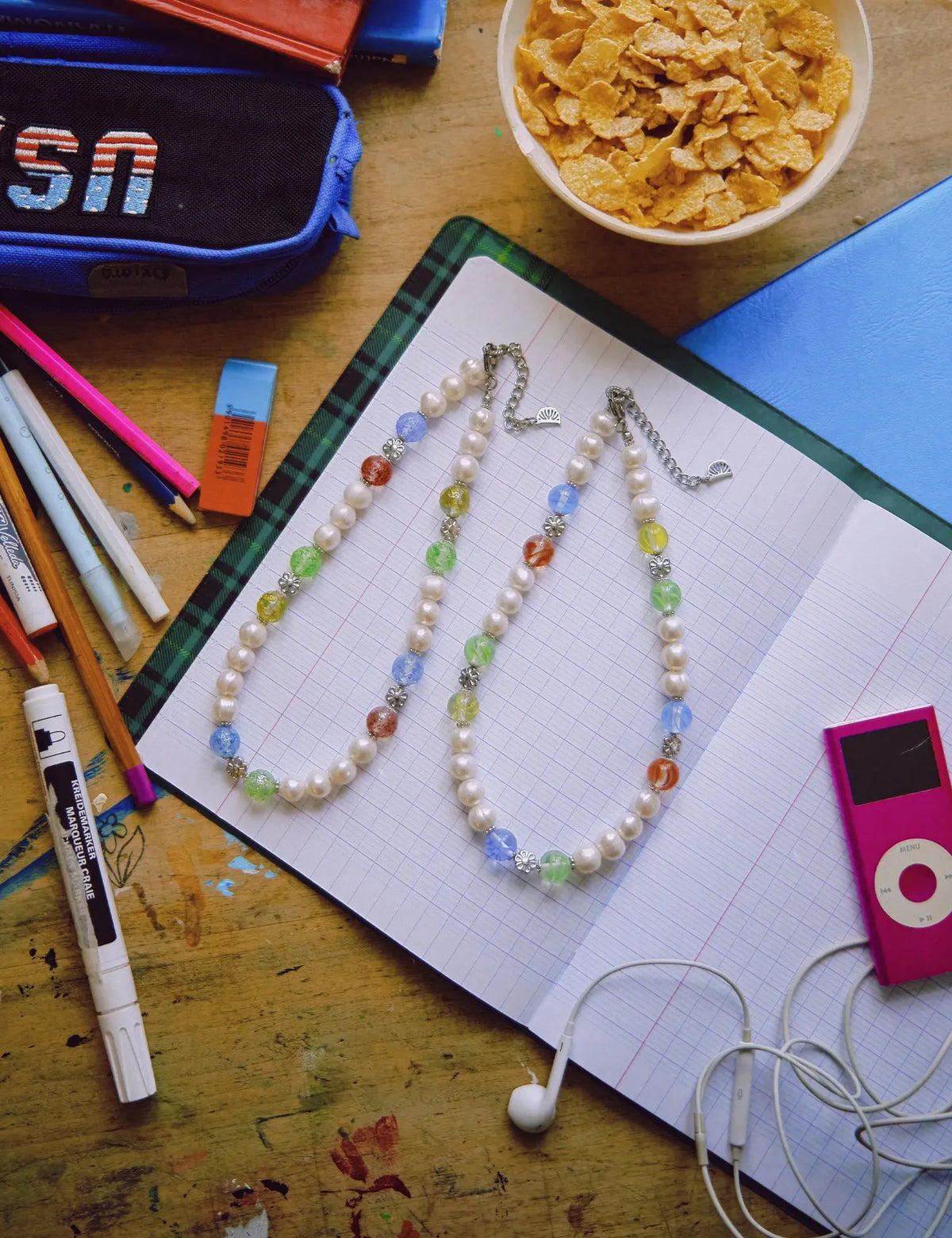 JIMMY and LIZZIE necklaces on a school notebook